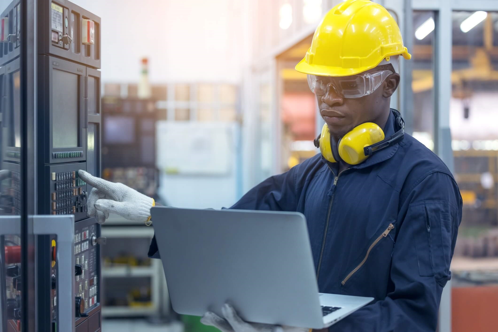 A MAP Engineering engineer wearing a hard hat and working on a computer at a manufacturing plant for pharmaceutical products